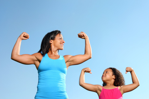 Mom and daughter flexing their muscles.
